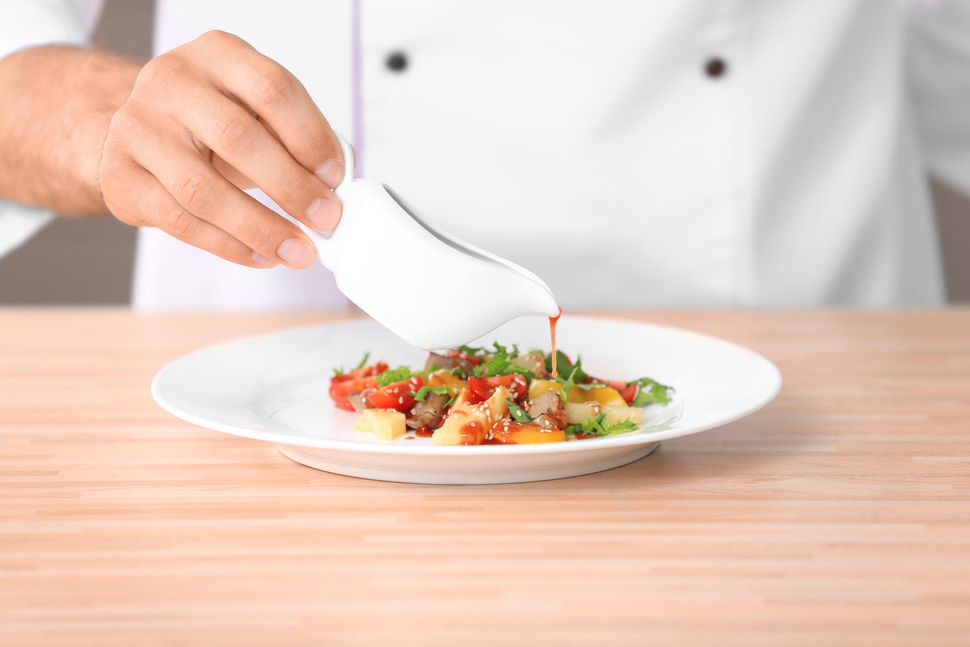 Closeup of plated dinner being finished by chef